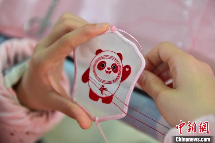圖為一名小學生正在繡制2022年北京冬奧會吉祥物“冰墩墩”形象。　喻云亮 攝