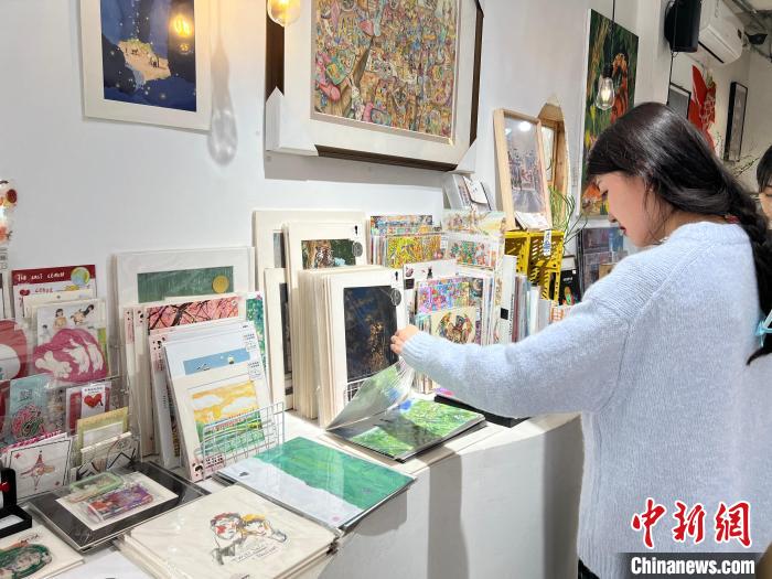 圖為藝術(shù)品商店內(nèi)，顧客挑選插畫作品。　鐘旖 攝