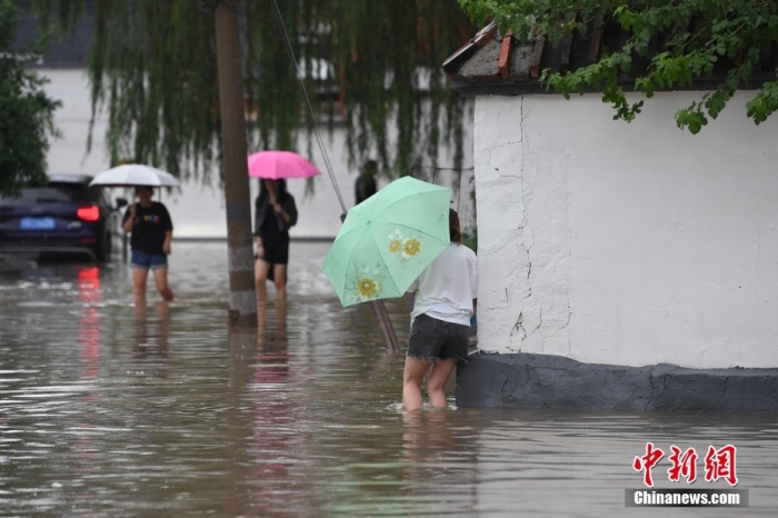 7月31日，市民行走在雨中的北京房山區(qū)瓦窯頭村。北京市氣象臺當日10時發(fā)布分區(qū)域暴雨紅色預警信號。北京市水文總站發(fā)布洪水紅色預警，預計當日12時至14時，房山區(qū)大石河流域將出現(xiàn)紅色預警標準洪水。<a target='_blank' href='/'><p  align=