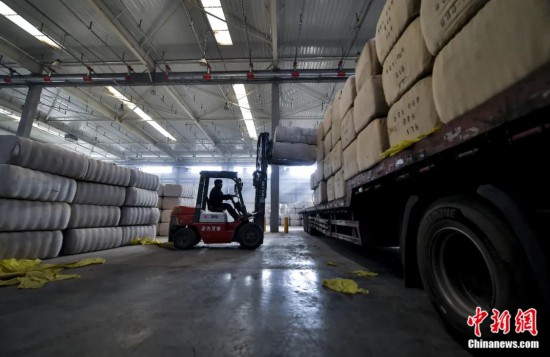 新疆喀什綜合保稅區(qū)，喀什啟路國際貿易有限公司的倉庫內，工人正在裝載從塔吉克斯坦和烏茲別克斯坦進口的棉花。劉新攝