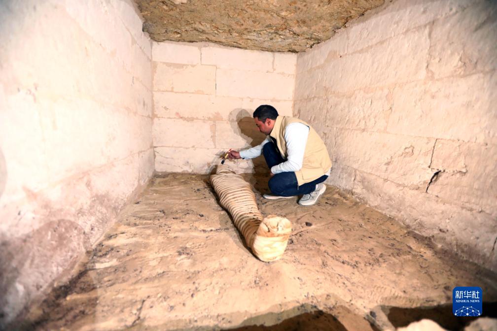 10月15日，在埃及明亞省考古現(xiàn)場，考古人員清理一座石鑿墓中的木乃伊。新華社發(fā)（艾哈邁德·戈馬攝）