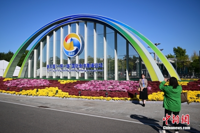 10月15日，北京，工作人員在國家會議中心外的第三屆“一帶一路”國際合作高峰論壇景觀布置前拍照留念。當日，位于國家會議中心的第三屆“一帶一路”國際合作高峰論壇新聞中心啟動試運行。據(jù)悉，第三屆“一帶一路”國際合作高峰論壇將于10月17日至18日在北京舉行。<a target='_blank' href='/'><p  align=