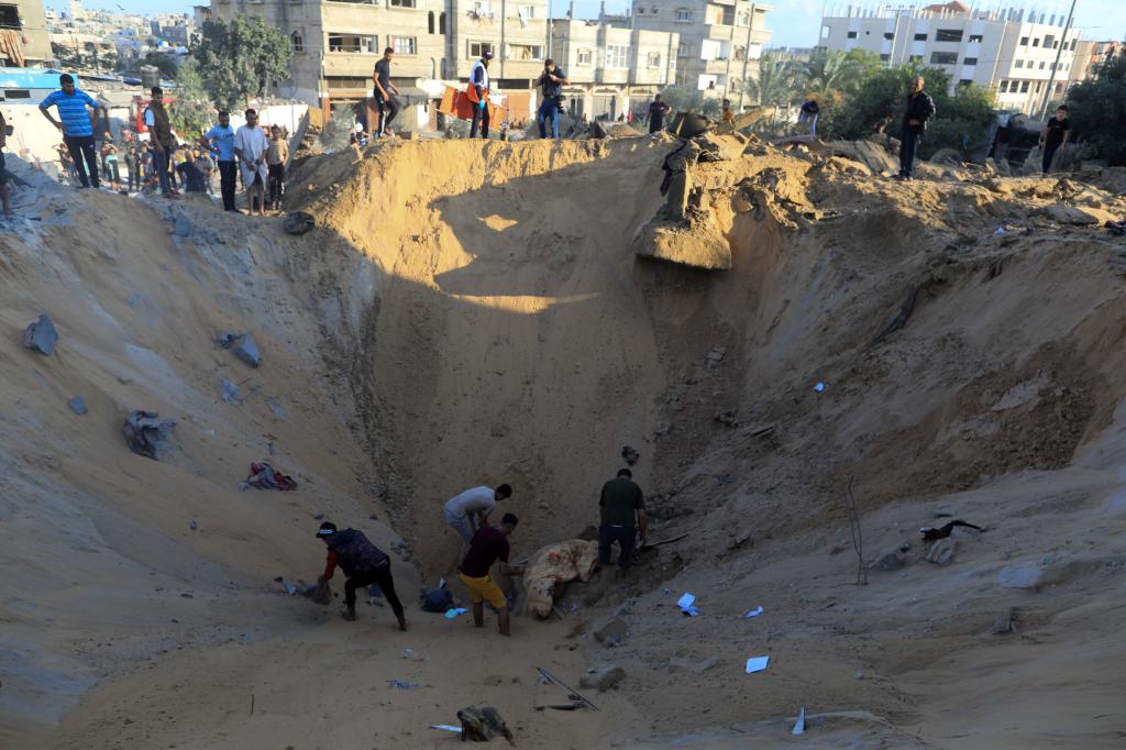 10月16日，在加沙地帶南部城市汗尤尼斯，人們在遭以色列襲擊后的建筑廢墟中救援傷者。 新華社發(fā)（亞西爾·庫迪 攝）