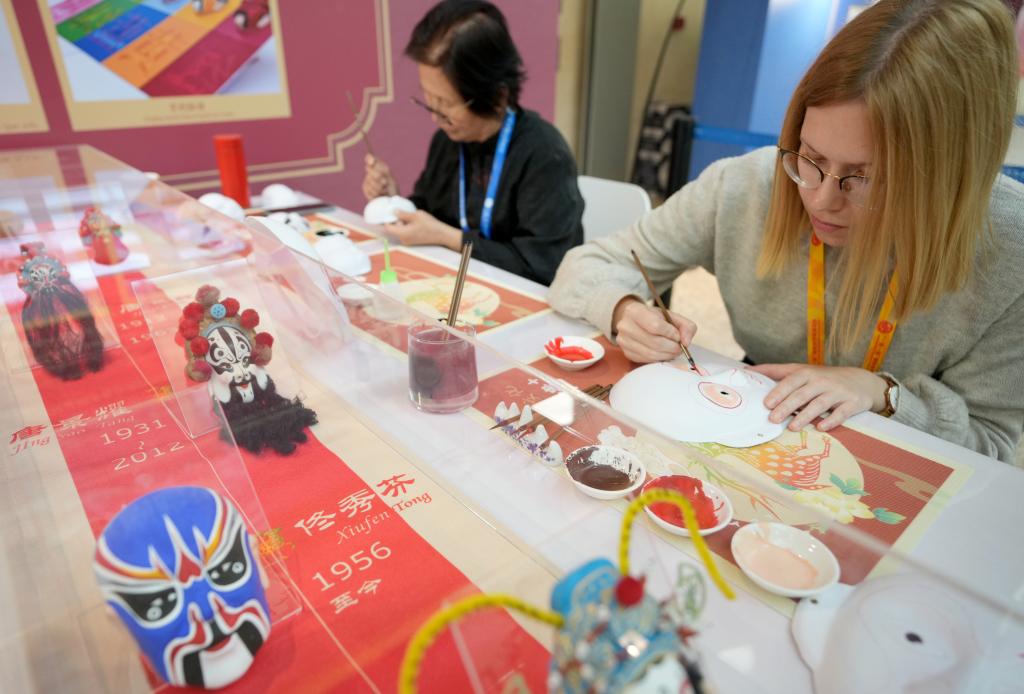 10月16日，在第三屆“一帶一路”國際合作高峰論壇新聞中心，來自比利時的記者（右）體驗畫京劇臉譜。新華社記者 王毓國 攝