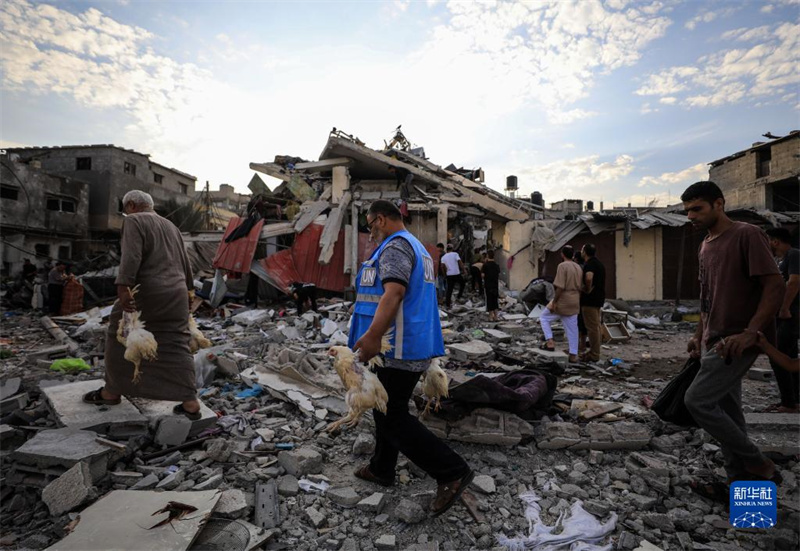 10月27日，在加沙地帶南部城市汗尤尼斯，人們經(jīng)過(guò)以軍襲擊后的房屋廢墟。