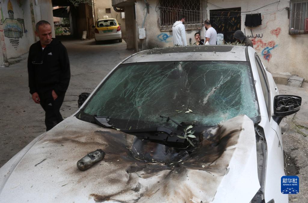 12月17日，在約旦河西岸城市圖勒凱爾姆附近的一處難民營，人們查看在沖突中損毀的車輛。新華社發(fā)（尼達(dá)爾·艾仕塔耶?dāng)z）
