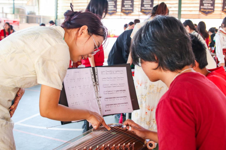 志愿者教師指導學生彈奏古箏?；顒又鬓k方供圖