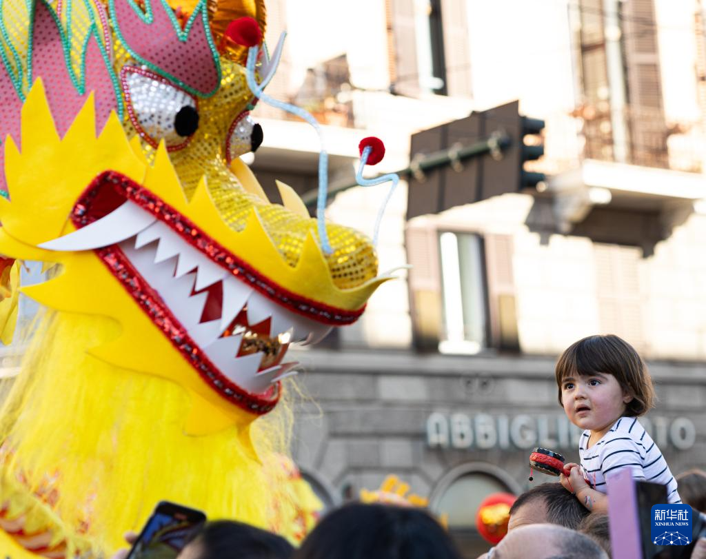 2月18日，在意大利羅馬，一名小朋友在彩妝巡游上觀看舞龍。新華社記者 李京 攝