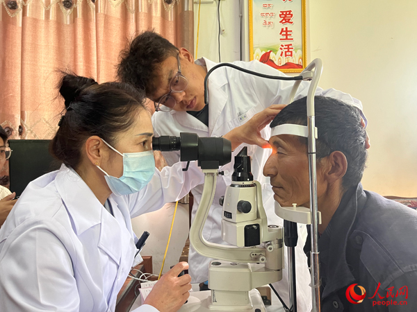 王紅英（左）和團隊成員為達(dá)熱村村民檢查眼睛。人民網(wǎng)記者 杜燕飛攝