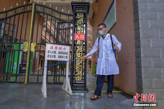 資料圖：?？诮?jīng)濟(jì)學(xué)院的工作人員在學(xué)生宿舍樓入口消毒。 中新社記者 駱云飛 攝