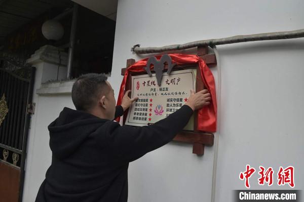 桂溪鎮(zhèn)渭溝村政府工作人員為“十星級文明戶”掛上牌匾。　楊勇 攝