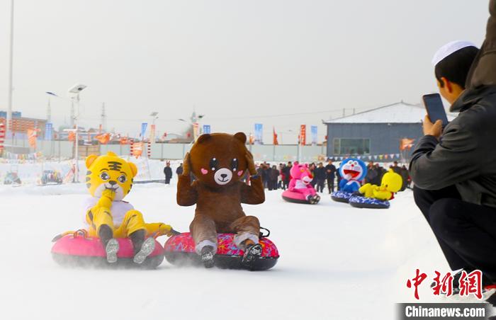 圖為臨夏市南龍鎮(zhèn)馬家莊村舉辦的鄉(xiāng)村文化旅游節(jié)上，游客穿著卡通服裝在體驗(yàn)雪上飛碟項(xiàng)目。近年來，臨夏州形成了“春賞花、夏避暑、秋摘果、冬玩雪”的全季節(jié)旅游產(chǎn)品體系。(資料圖) 高展 攝