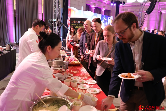 當(dāng)?shù)貢r(shí)間3月7日晚，華盛頓聯(lián)合車(chē)站廣場(chǎng)舉行駐美使團(tuán)“使館主廚挑戰(zhàn)賽”。圖為當(dāng)?shù)孛癖娫谥袊?guó)展臺(tái)前體驗(yàn)中國(guó)美食。人民網(wǎng)記者 李志偉攝