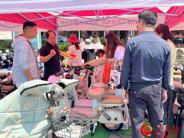 某電動自行車品牌工作人員向消費者介紹以舊換新相關(guān)情況。人民網(wǎng)記者 杜燕飛攝