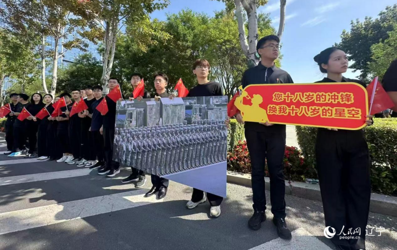沈陽市人民廣場上，大學生們手持閱兵的圖片，告慰英烈。人民網(wǎng)記者 周頌雪攝