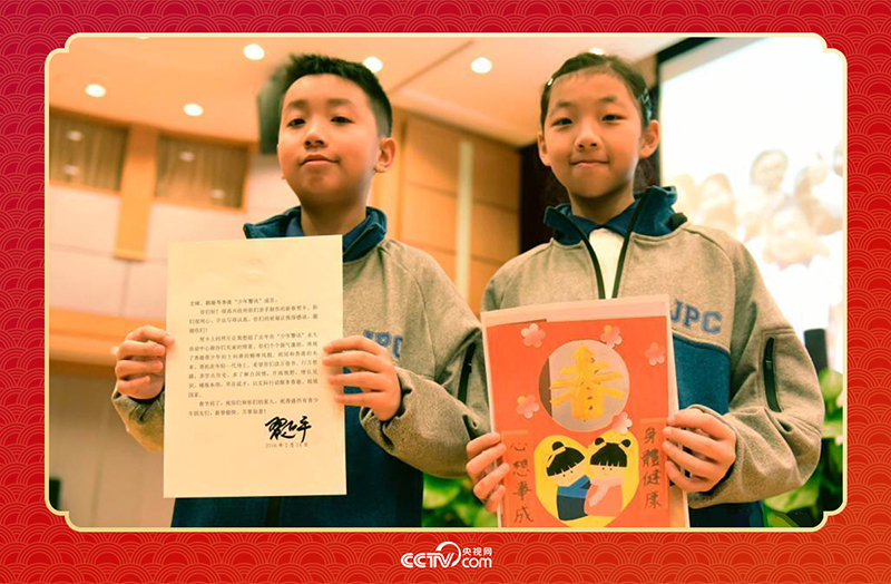 圖為香港“少年警訊”成員郭宏晞（左）展示習主席回信、羅顥凝（右）展示送給習主席的賀卡并合影。