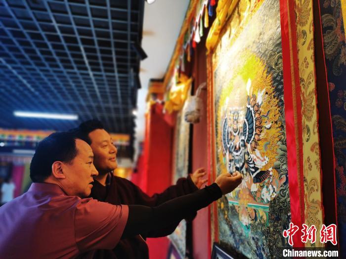 圖為久美尖措展示唐卡作品?！?zhí)砀?攝
