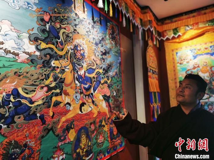 圖為久美尖措展示唐卡作品?！?zhí)砀?攝