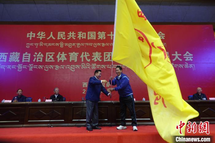 西藏自治區(qū)副主席甲熱·洛桑丹增授代表團團旗，西藏自治區(qū)體育局局長尼瑪次仁接旗?！∪轿木?攝