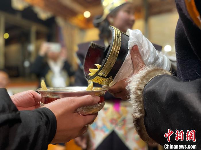 圖為主人在碗中斟滿青稞酒?！∪轿木?攝