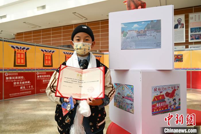 圖為一名獲獎學生與自己的繪畫作品合影?！≮w朗 攝