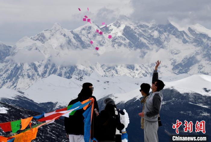 圖為5月14日，游客在西藏林芝色季拉山觀景臺拋灑“隆達”(風(fēng)馬旗，藏族民眾的一種祈福方式)。　李林 攝