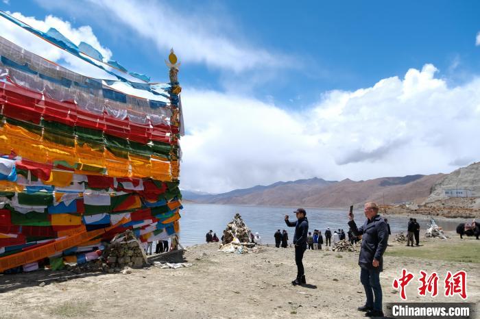 進(jìn)藏參訪嘉賓在羊湖畔拍攝經(jīng)幡?！〗w波 攝
