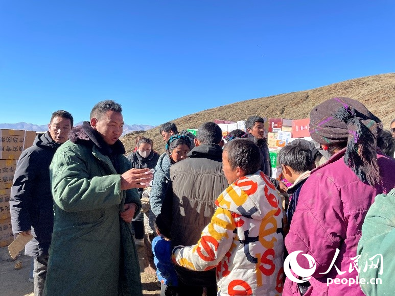 定日縣公安局干警頓珠次仁（左二）正在協(xié)助分發(fā)物資。人民網(wǎng)記者 郝潔攝