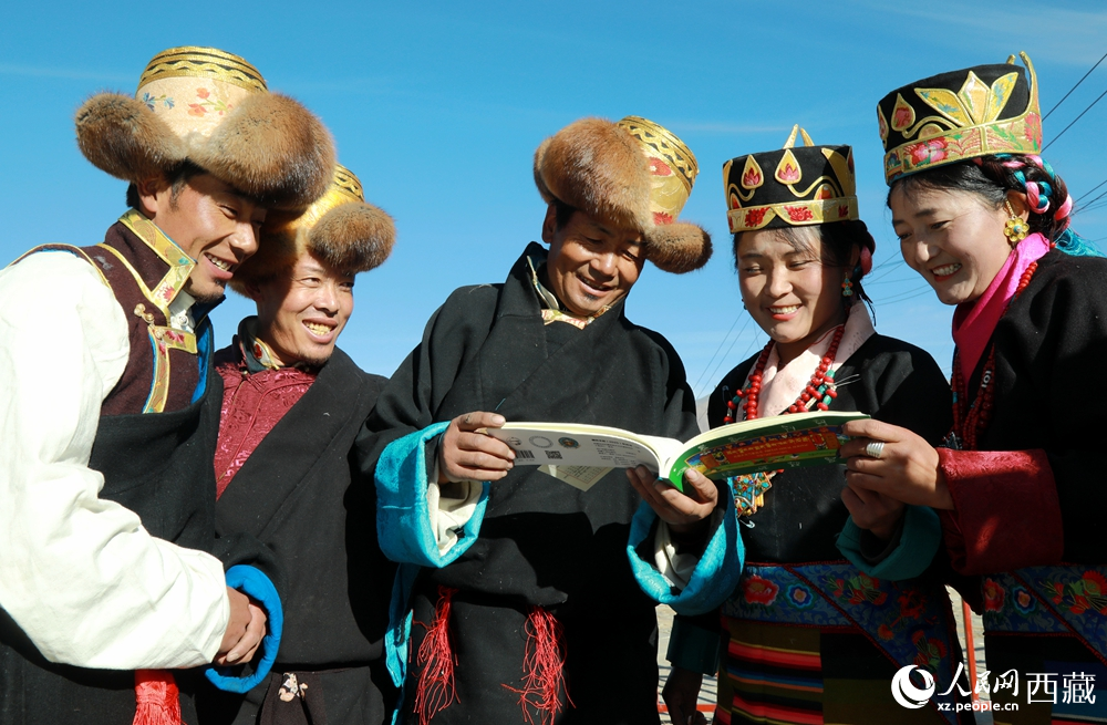 鄉(xiāng)親們身著民族盛裝，圍站在一起認(rèn)真翻看日歷，共話農(nóng)事安排與時(shí)節(jié)規(guī)律，笑容洋溢傳遞豐收期盼。人民網(wǎng)記者 吳雨仁攝