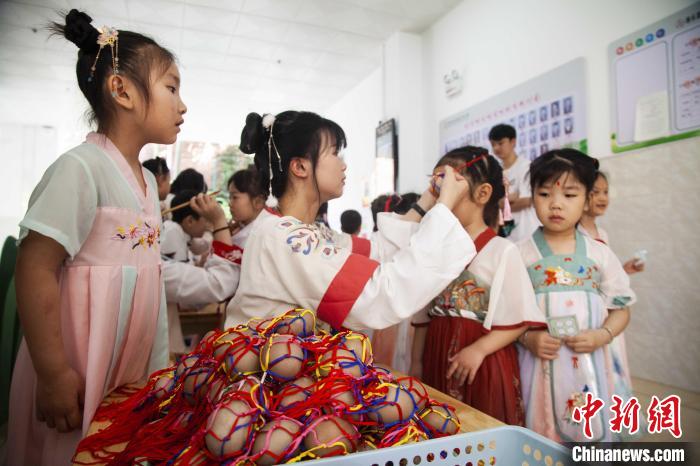 圖為幼兒園的老師們穿上漢服為小朋友們戴上彩蛋，寓意著幸福安康?！《^生 攝