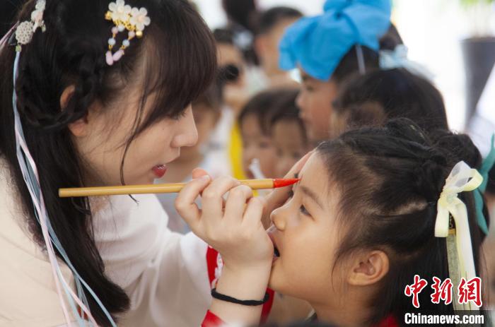 圖為老師在孩子們額頭上點(diǎn)上雄黃，驅(qū)邪辟禍?！《^生 攝